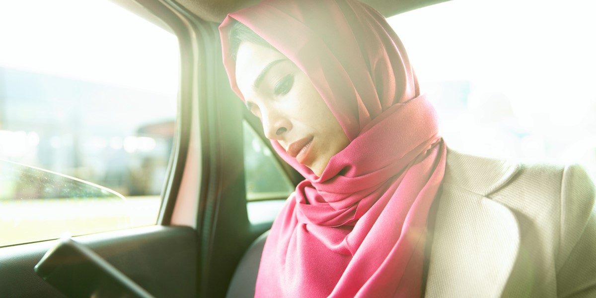 woman travelling by car, looking at cell phone in hand