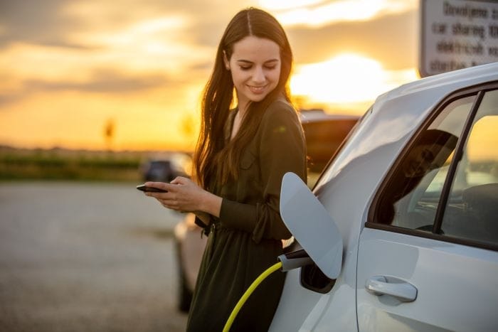 Woman smiling charging electric car